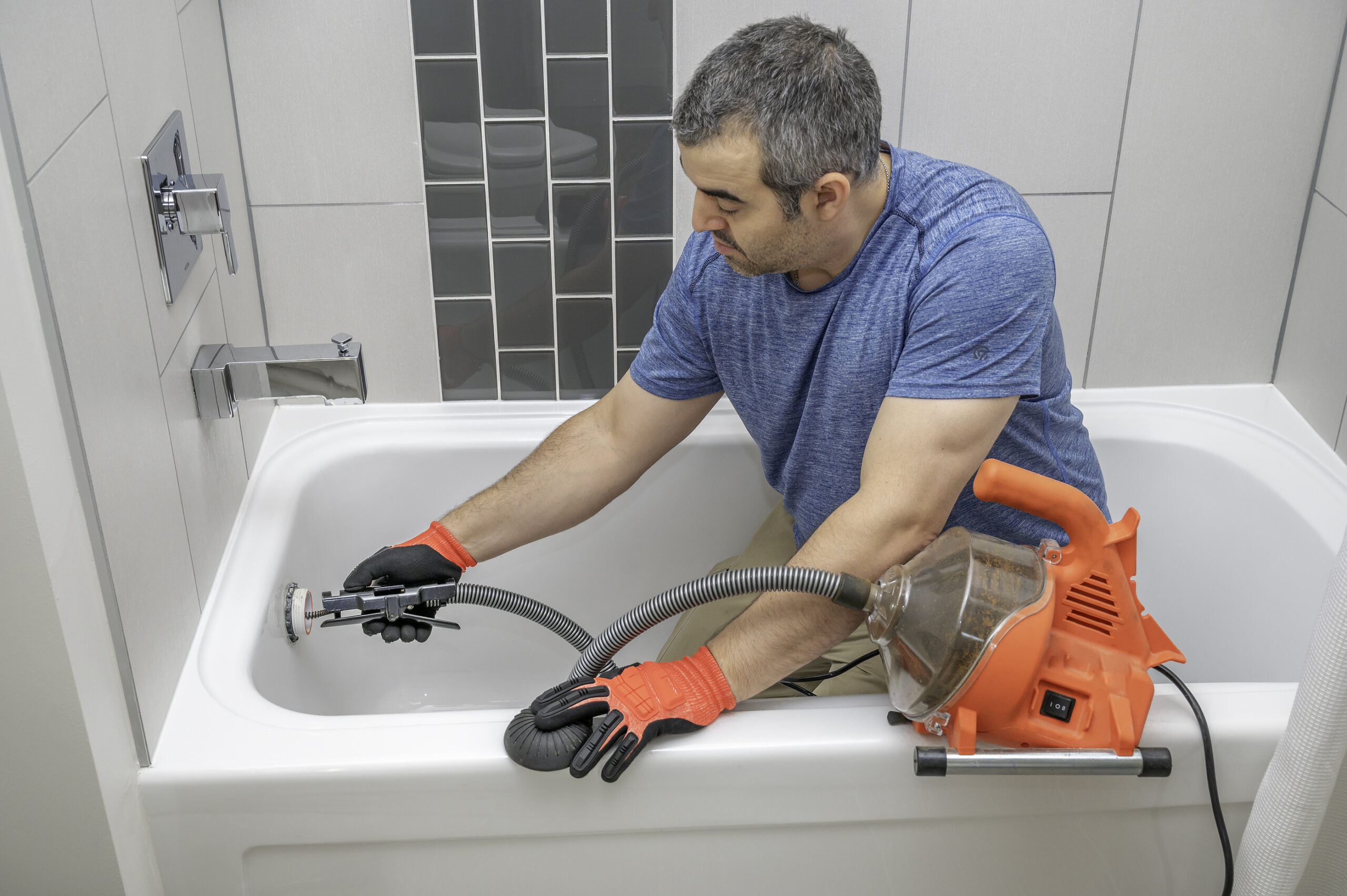 https://www.blockbusters.co.uk/wp-content/uploads/2022/03/Man-Using-A-Mini-Plumbers-Snake-to-unclog-bath-scaled.jpg